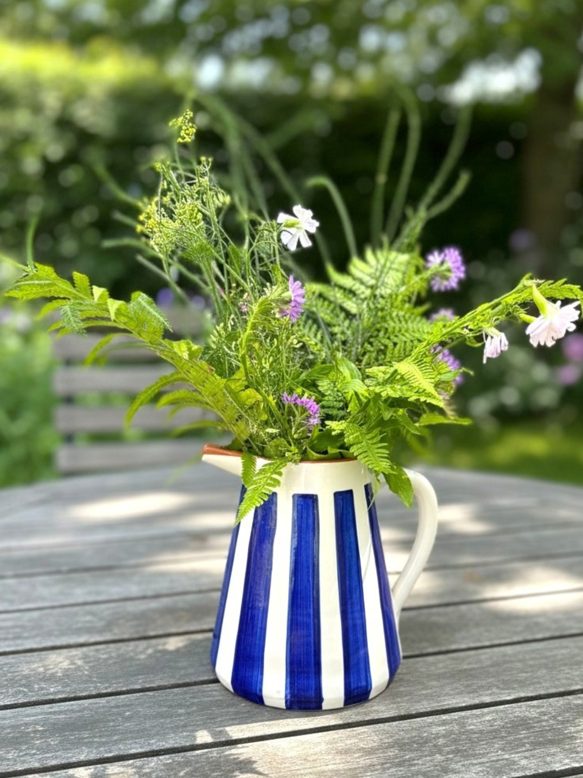 Casa Cubista Bold Stripe kande i terracotta med blå striber på havebord med blomster - håndlavet keramik fra Portugal