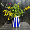 Casa Cubista Blå Bold Stripe kande med vilde blomster op ad sort mur