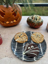 Casa Cubista sort Dash tallerkenfad med halloweenkager på havebord foran halloweengræsker