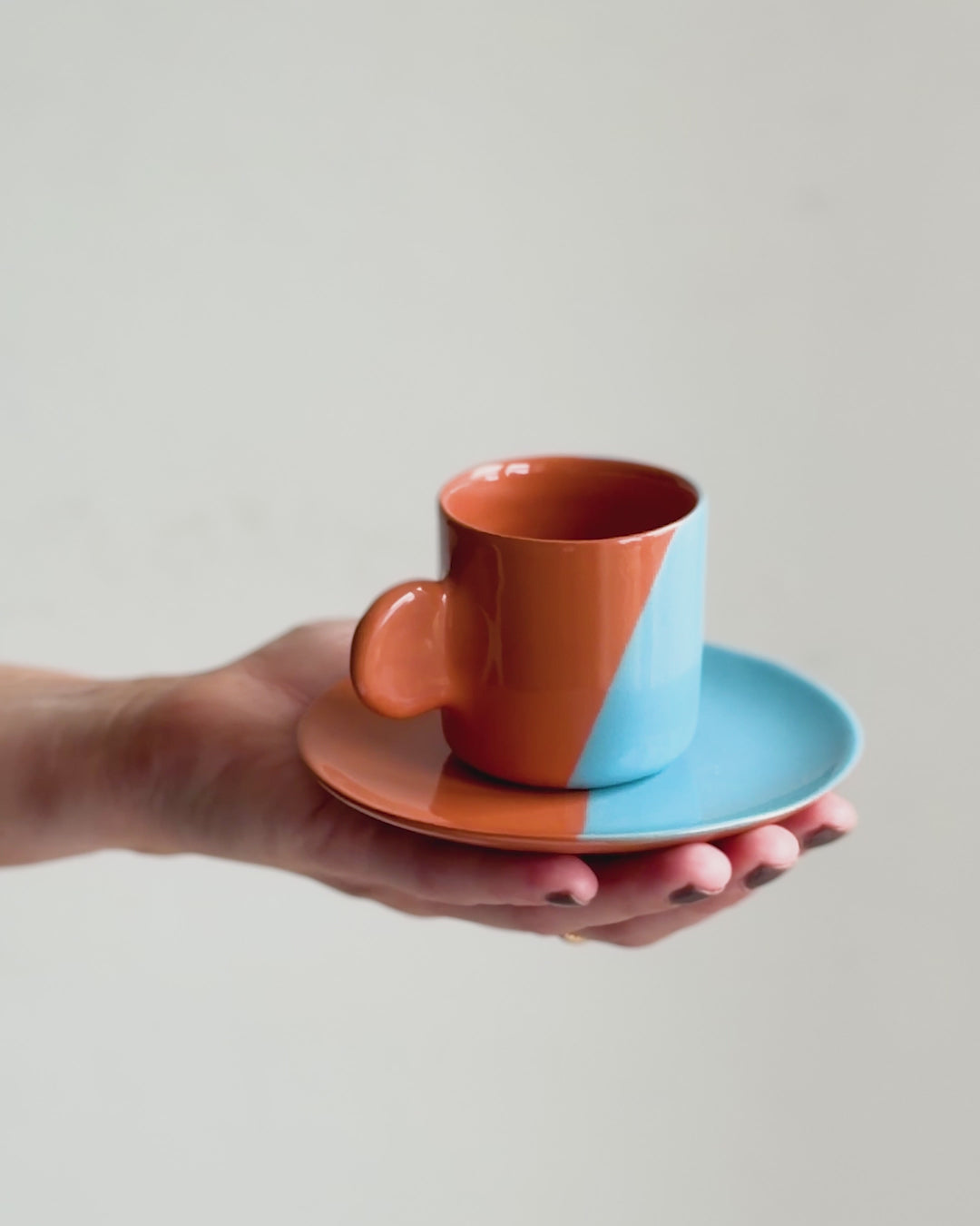 Casa Cubista Dipped espressokop i brun og aqua vist frem på en hånd - håndlavet terracotta fra Portugal